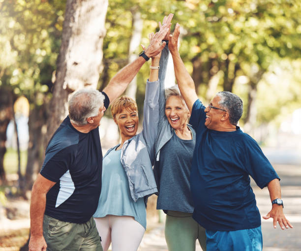 A group of older adults celebrating together outdoors with hands raised